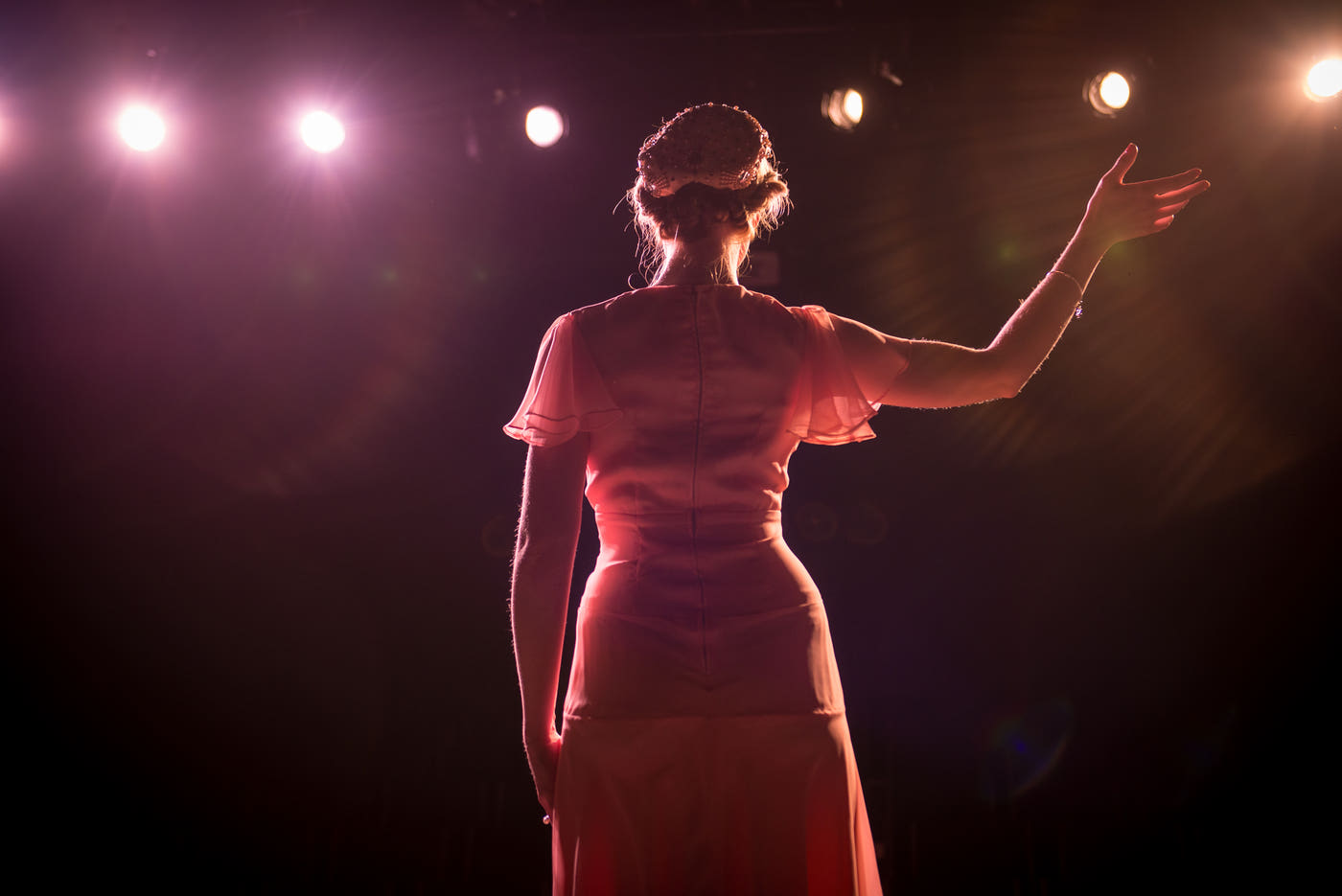 A woman speaking on stage under warm lights